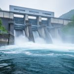 Hydroelectric dam spillway with rushing river water and turbine intake structure, conveying clean power generation.